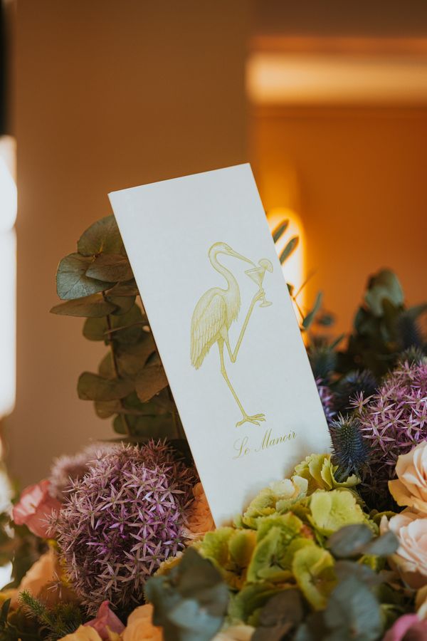 La carte du Manoir et son héron, posée parmi les fleurs